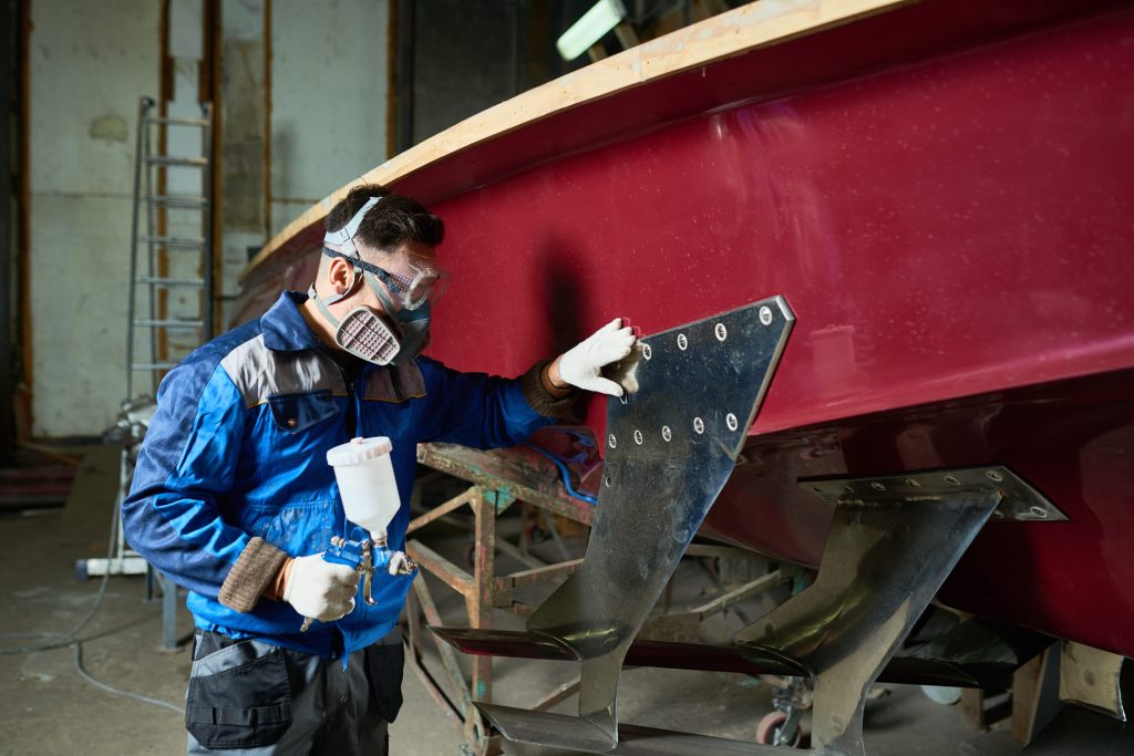 man painting boats in yacht workshop 9TMXSW3