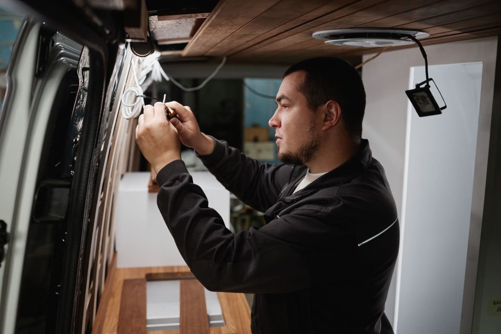 man putting electric wires in camper van 6VFMMKR