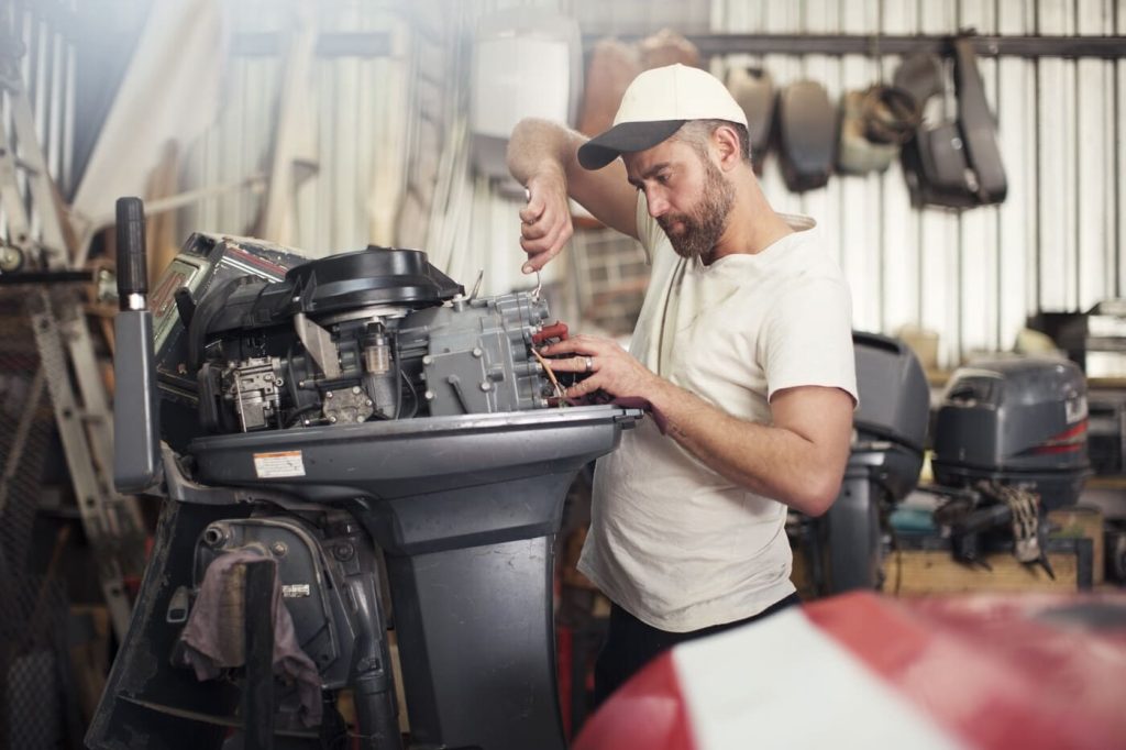 mechanic working on boat motor in a workshop LJH6MV2